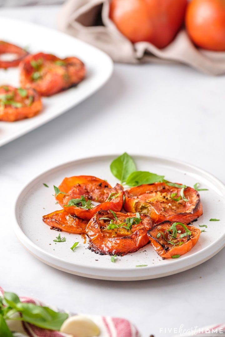 Roasted Tomatoes on plate with basil.