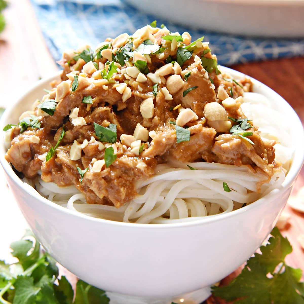 Slow Cooker Thai Peanut Chicken over rice noodles in bowl.