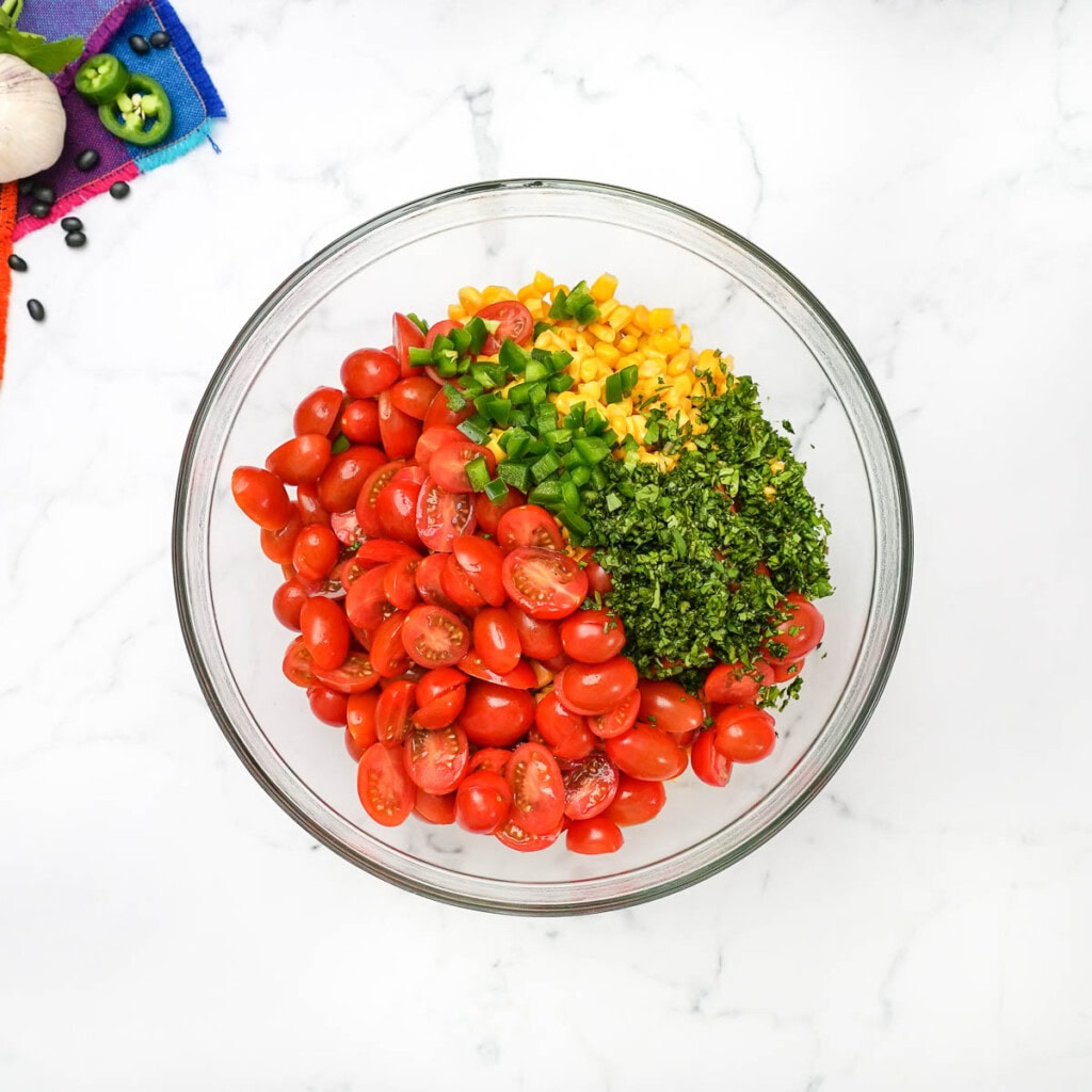 Adding cilantro and jalapeño to bowl for black bean corn salsa.