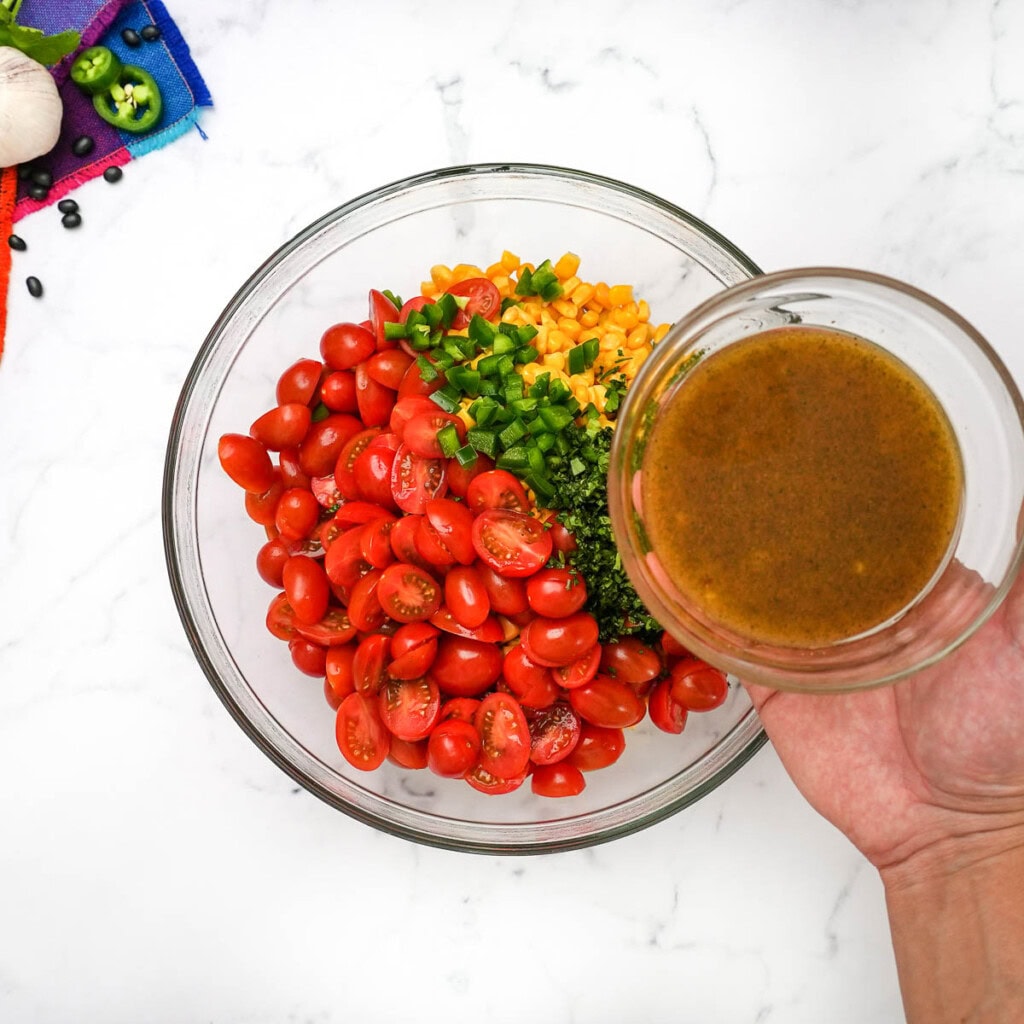 Pouring vinaigrette over corn and black bean salsa.