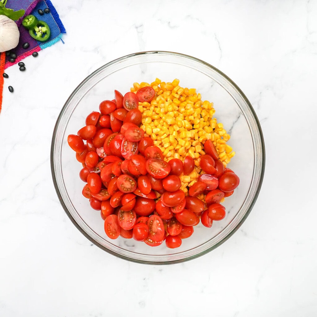 Corn and tomatoes added to bowl for corn black bean salsa.