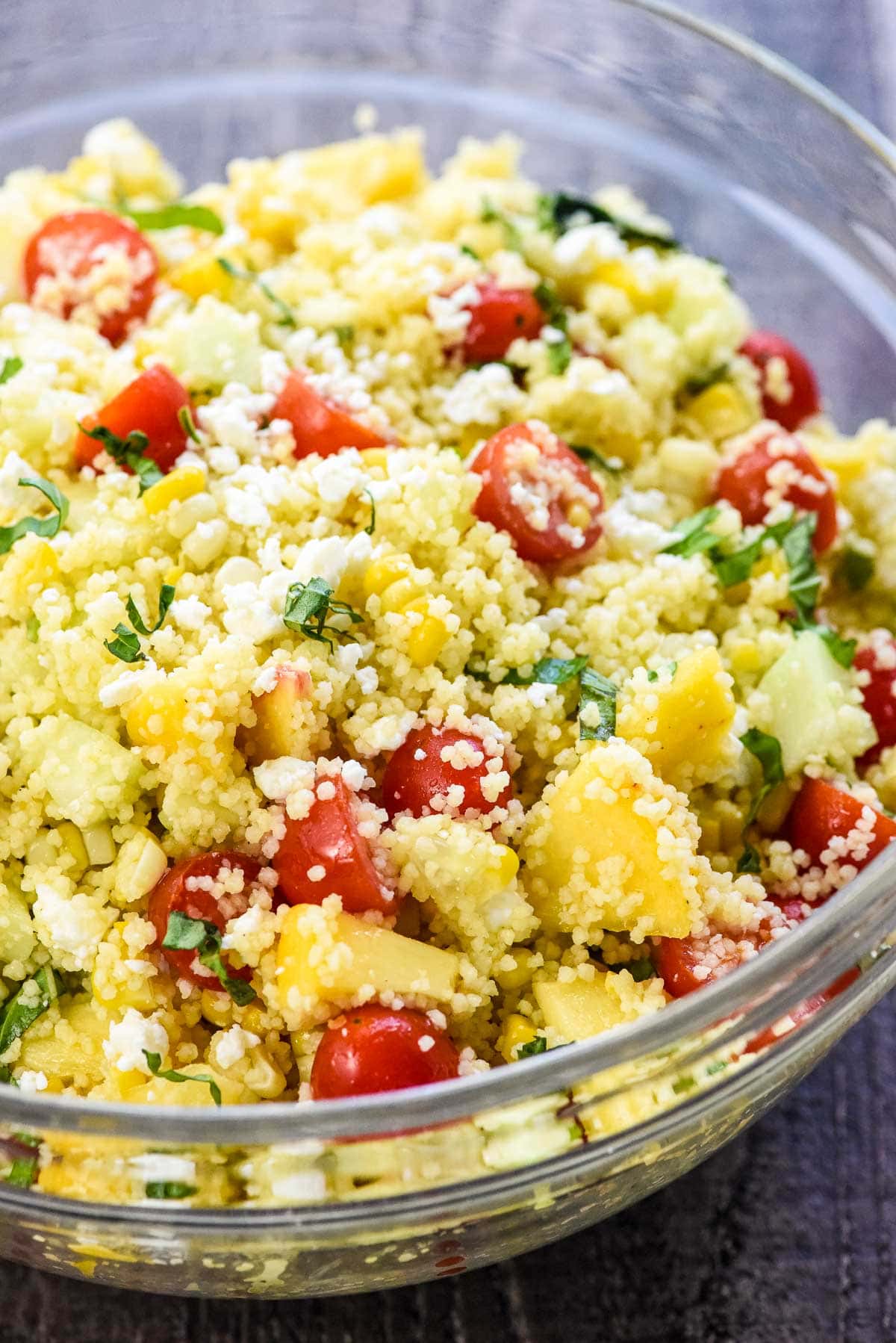 Couscous Salad in glass bowl with basil garnish.