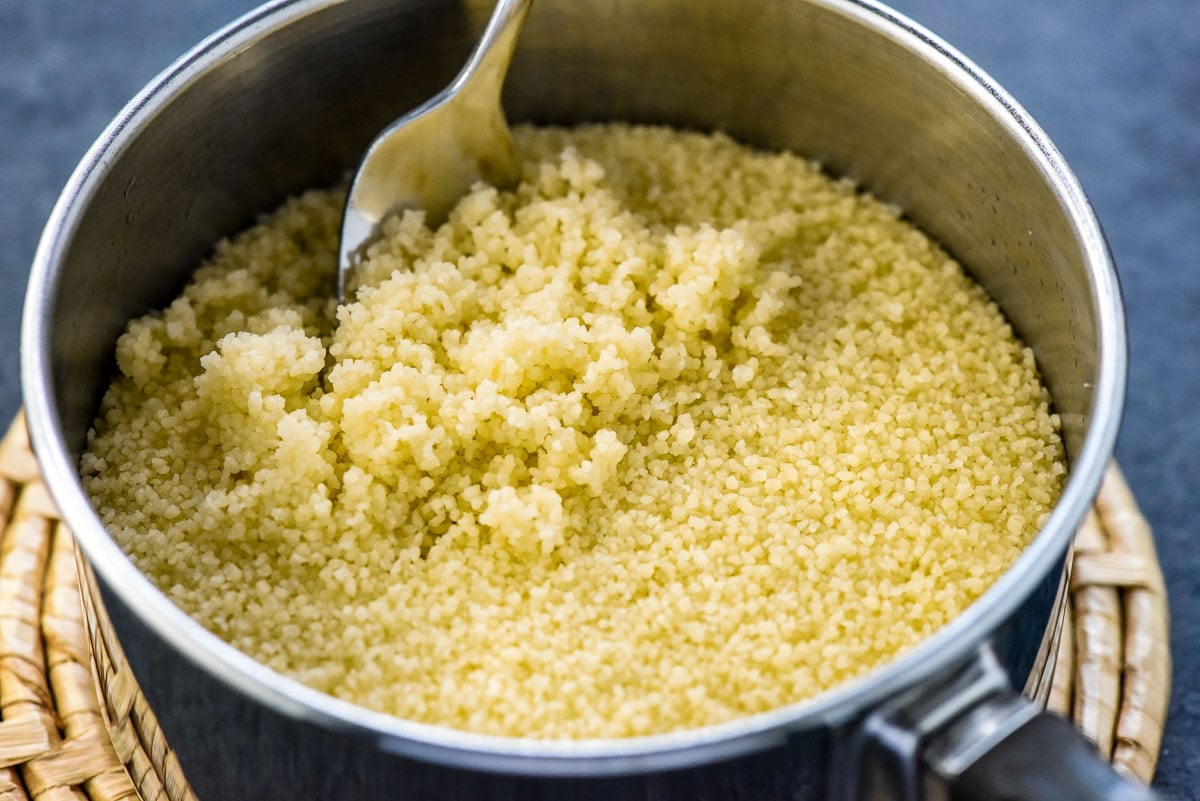 Fluffing couscous in pot with a fork.