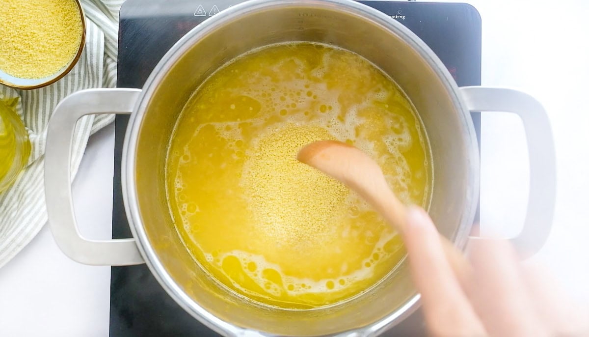 Adding couscous to pot.