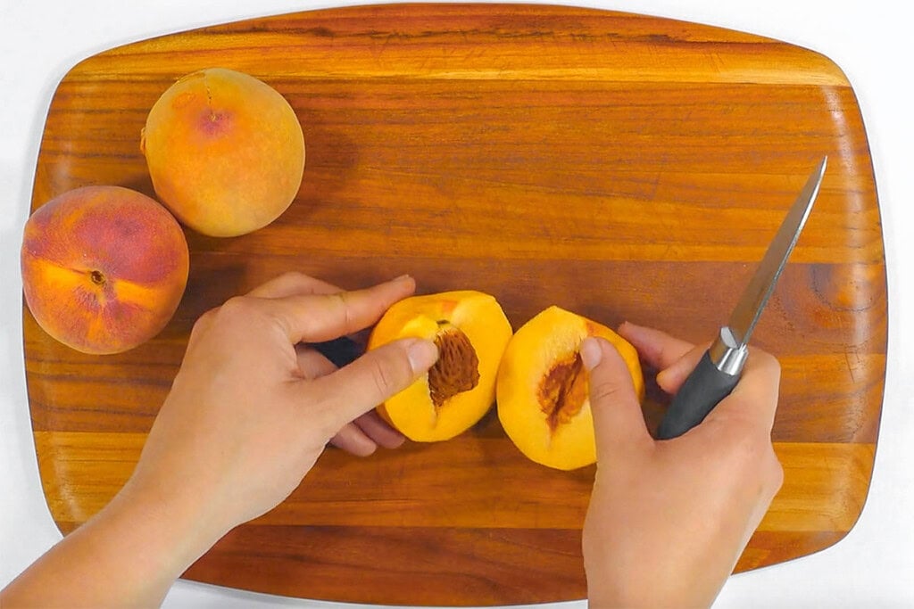 Slicing fresh peaches in half for peach cake recipe.