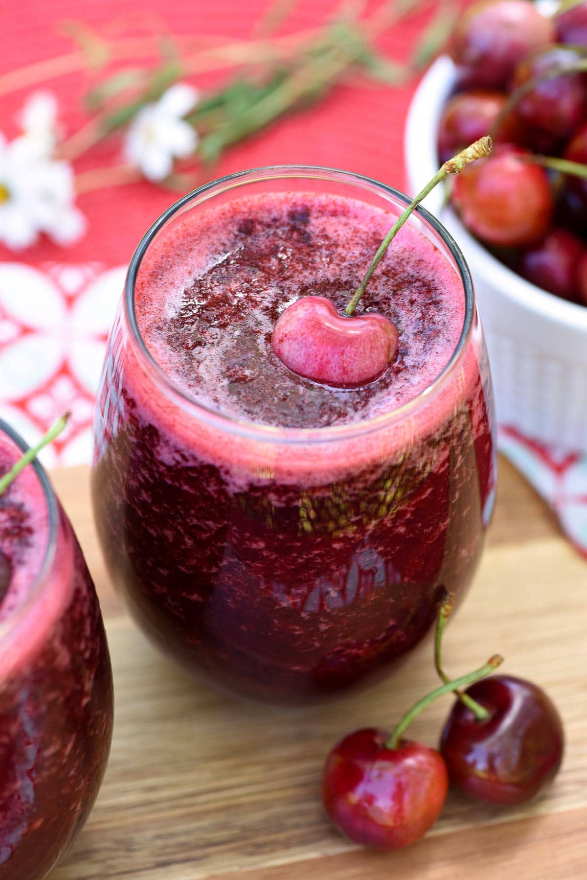 Wine slushies on table with cherries and flowers.