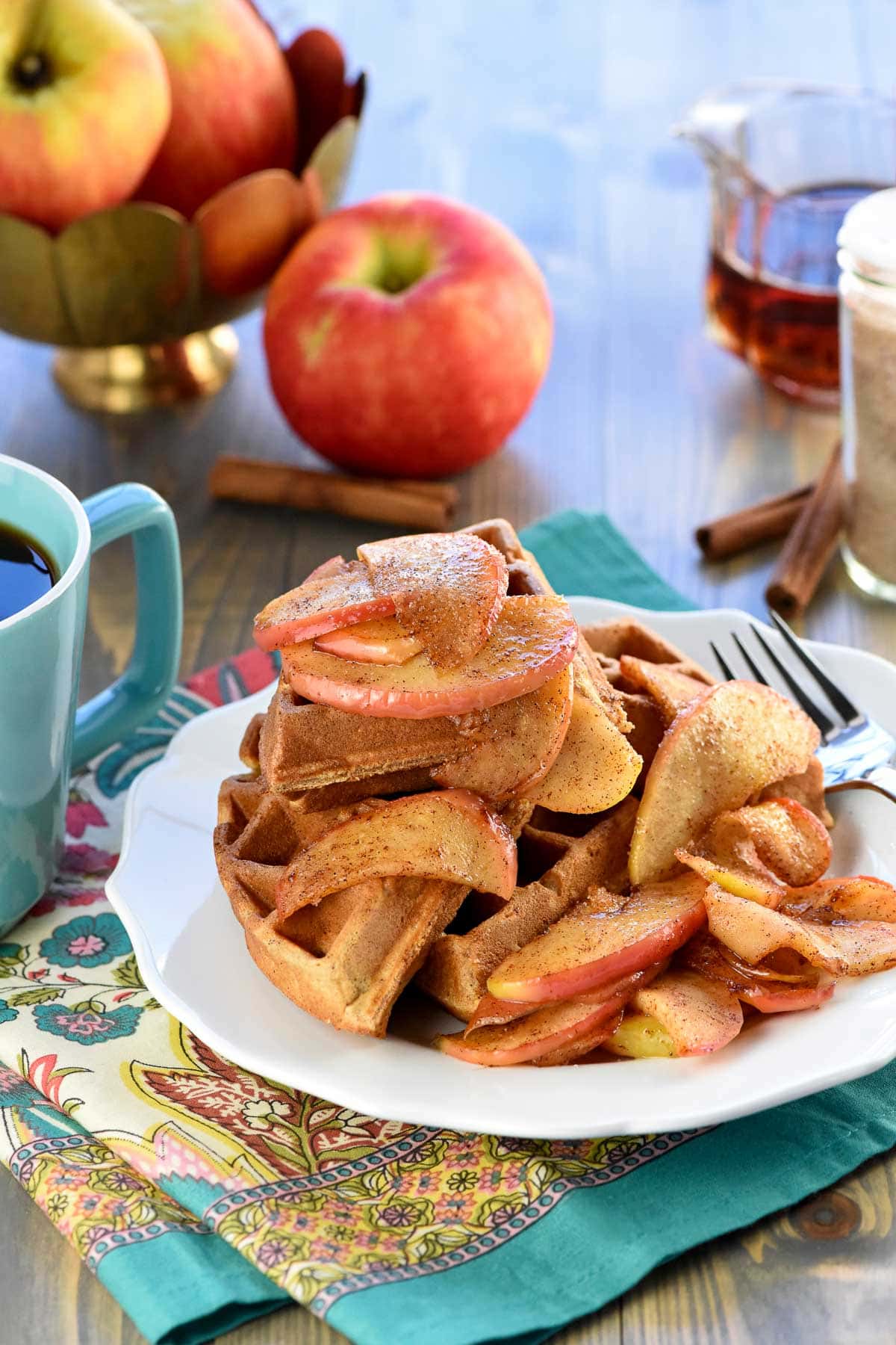 Apple Cinnamon Waffles on plate with apples in background.