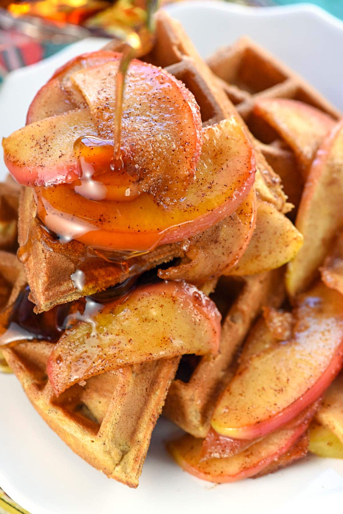 Pouring maple syrup over Apple Cinnamon Waffles.