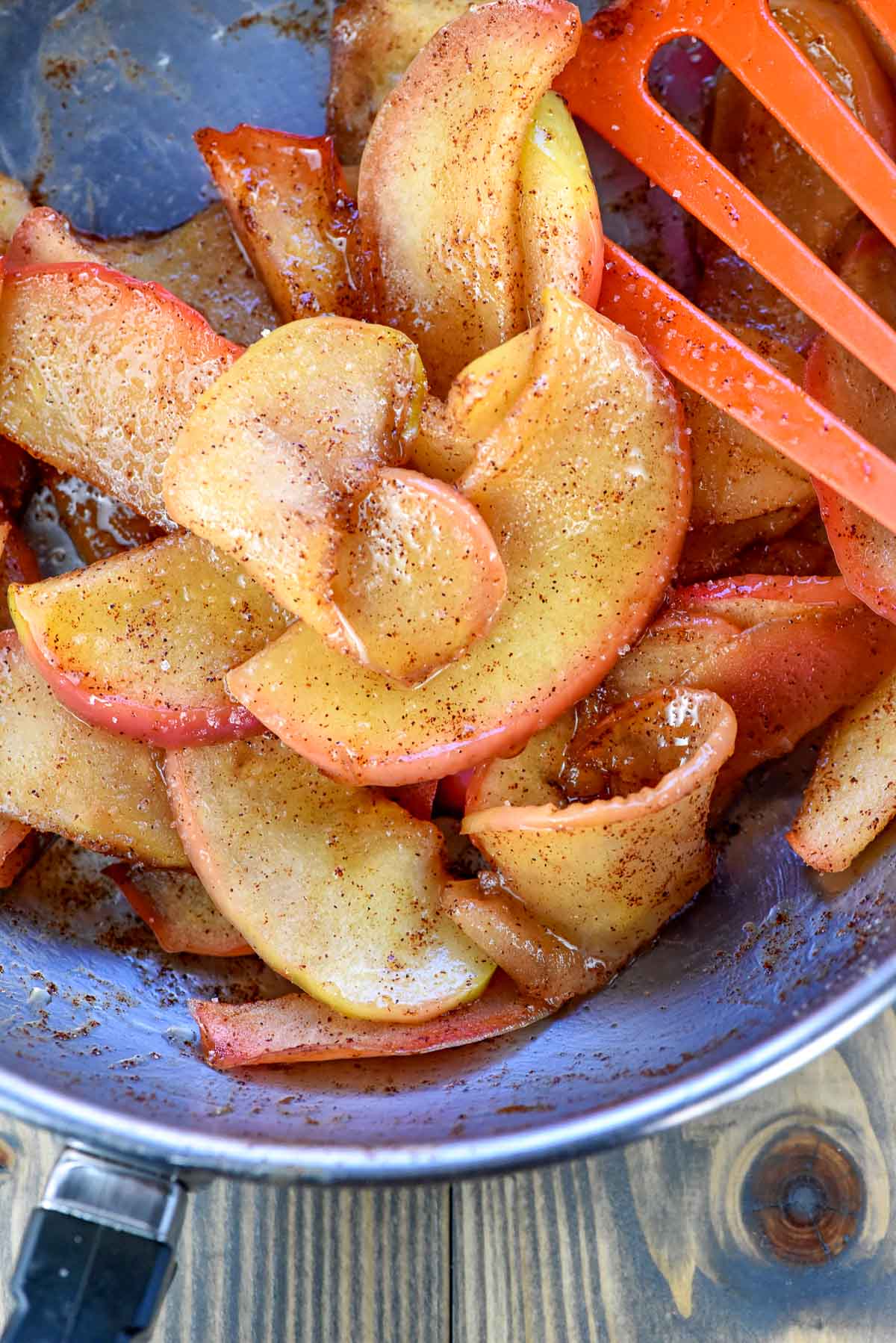 Sliced apples sauteed in pan with butter, cinnamon, and sugar.