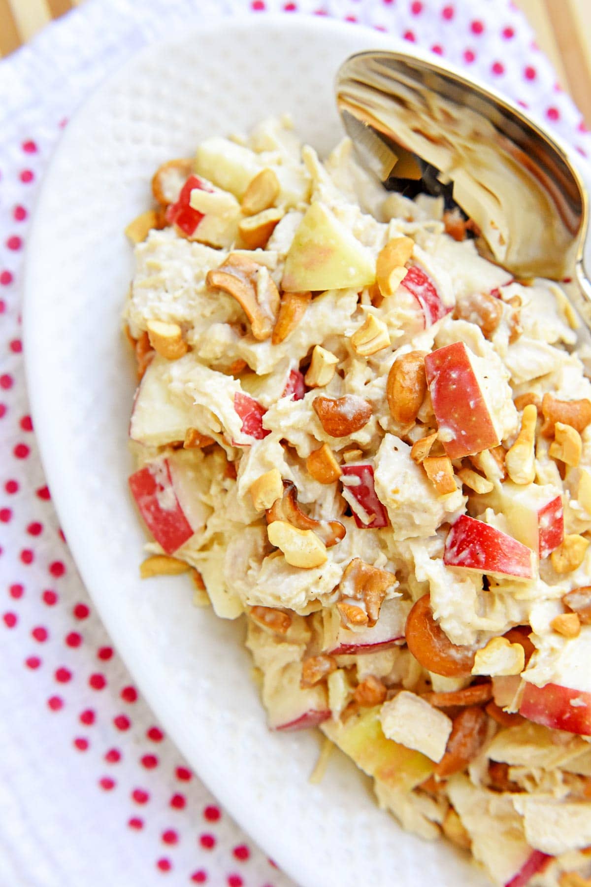 Aerial view of Chicken Salad with Apples on a white platter with a spoon.