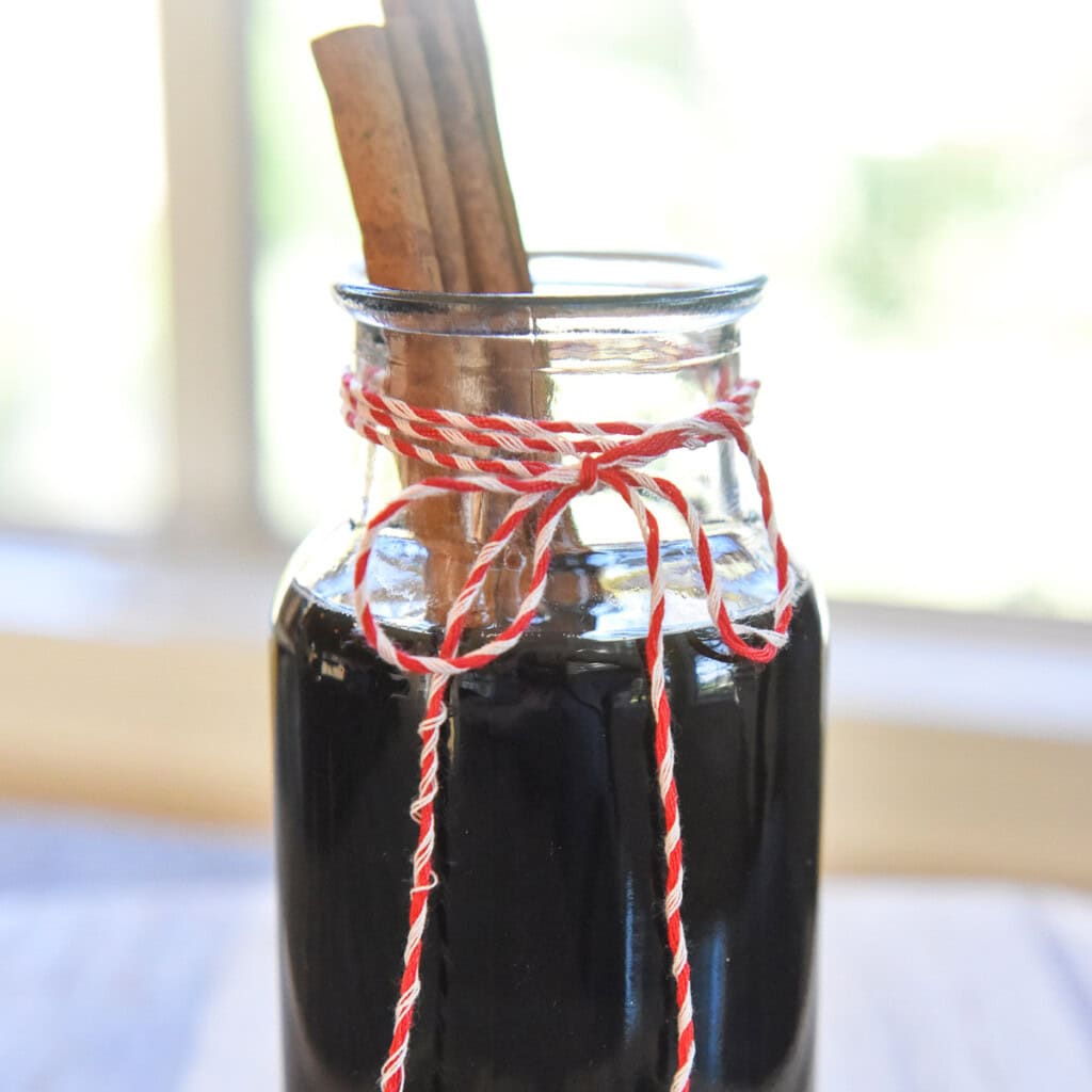 Cinnamon Dolce Syrup in glass jar with cinnamon sticks.