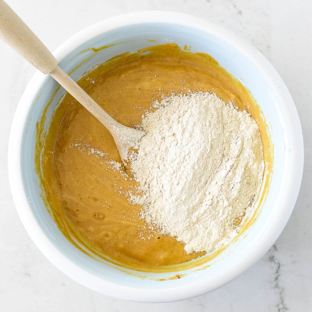 Adding remaining flour to Healthy Pumpkin Muffins recipe.