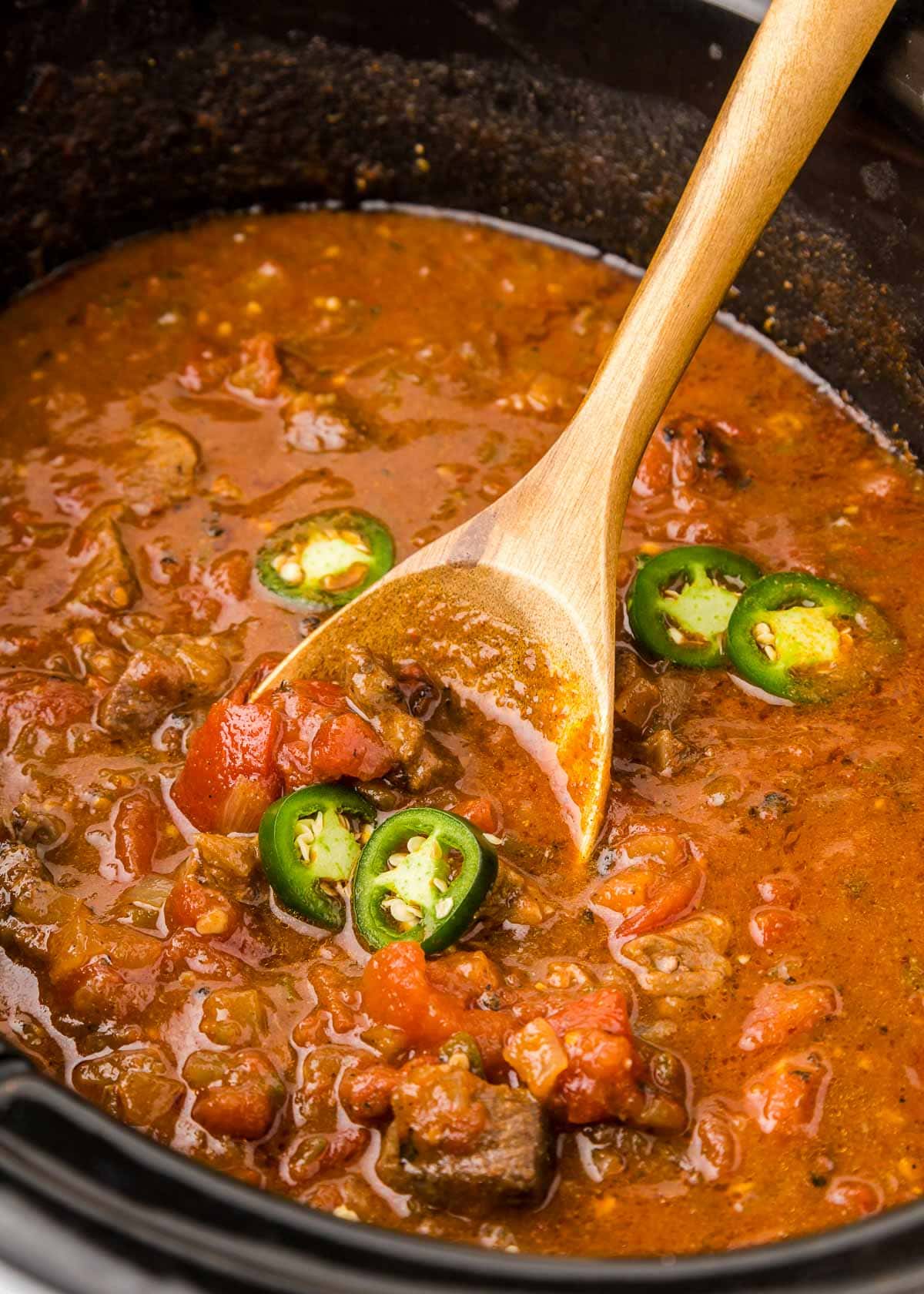 Texas Chili scooped with wooden spoon.