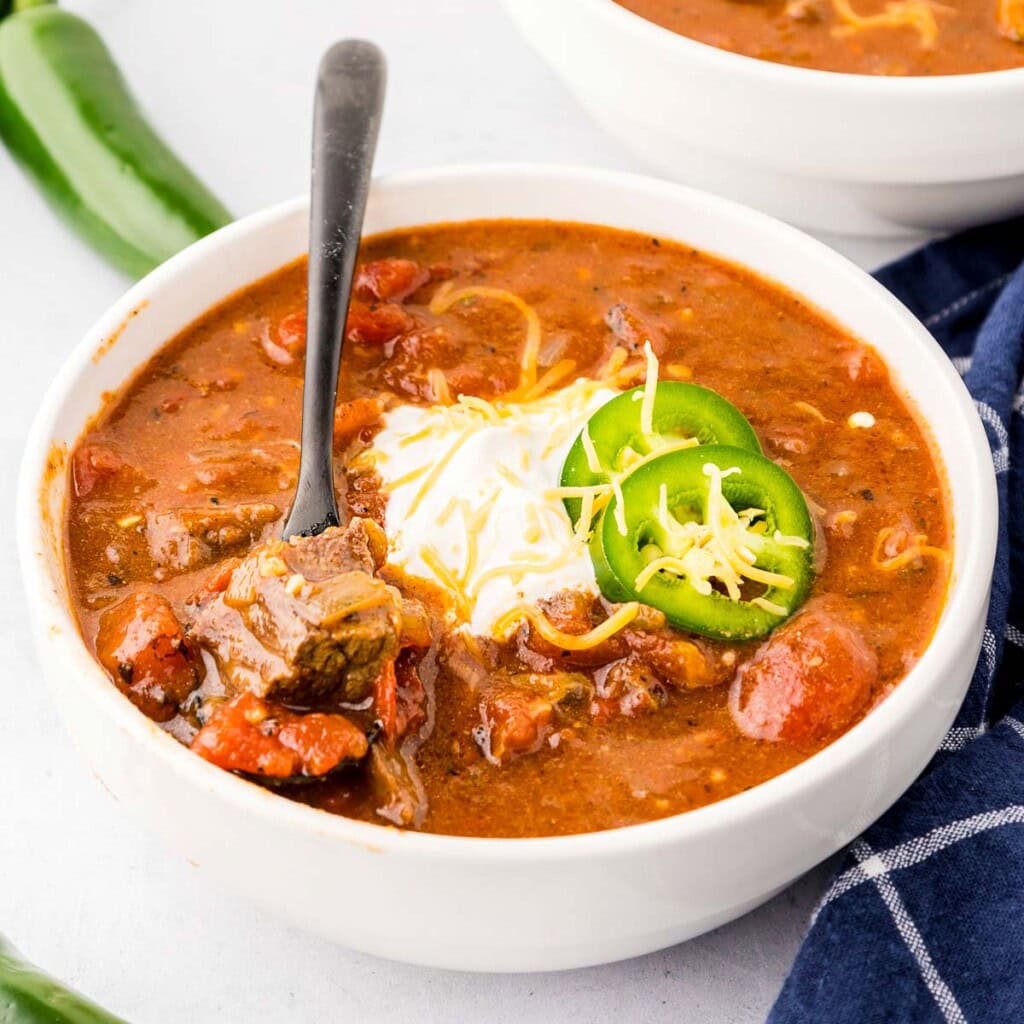 Texas Chili recipe in bowl with spoon and garnishes.