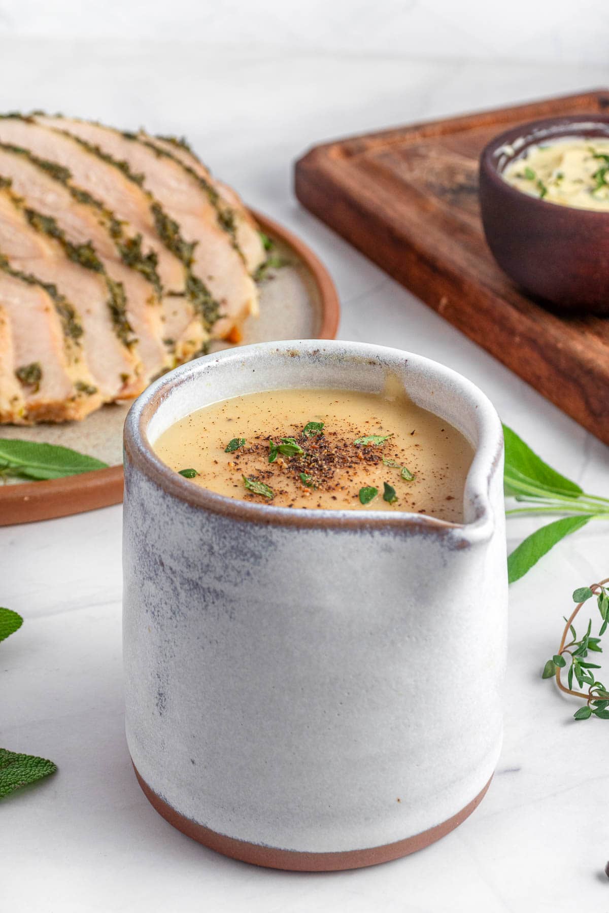 Make Ahead Turkey Gravy with fresh herbs on table.