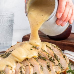 Make Ahead Turkey Gravy pouring over slices of turkey breast.