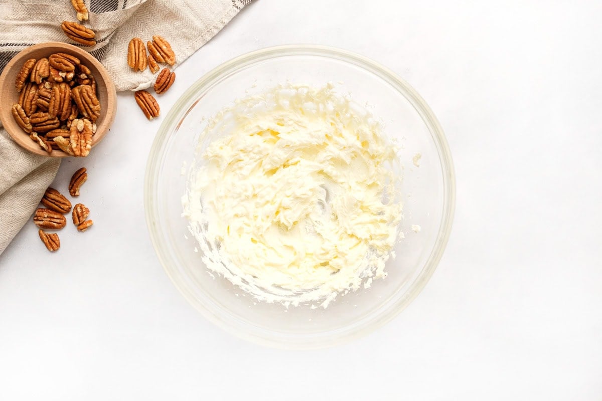 Beating cream cheese and butter together for mini pecan pies recipe.