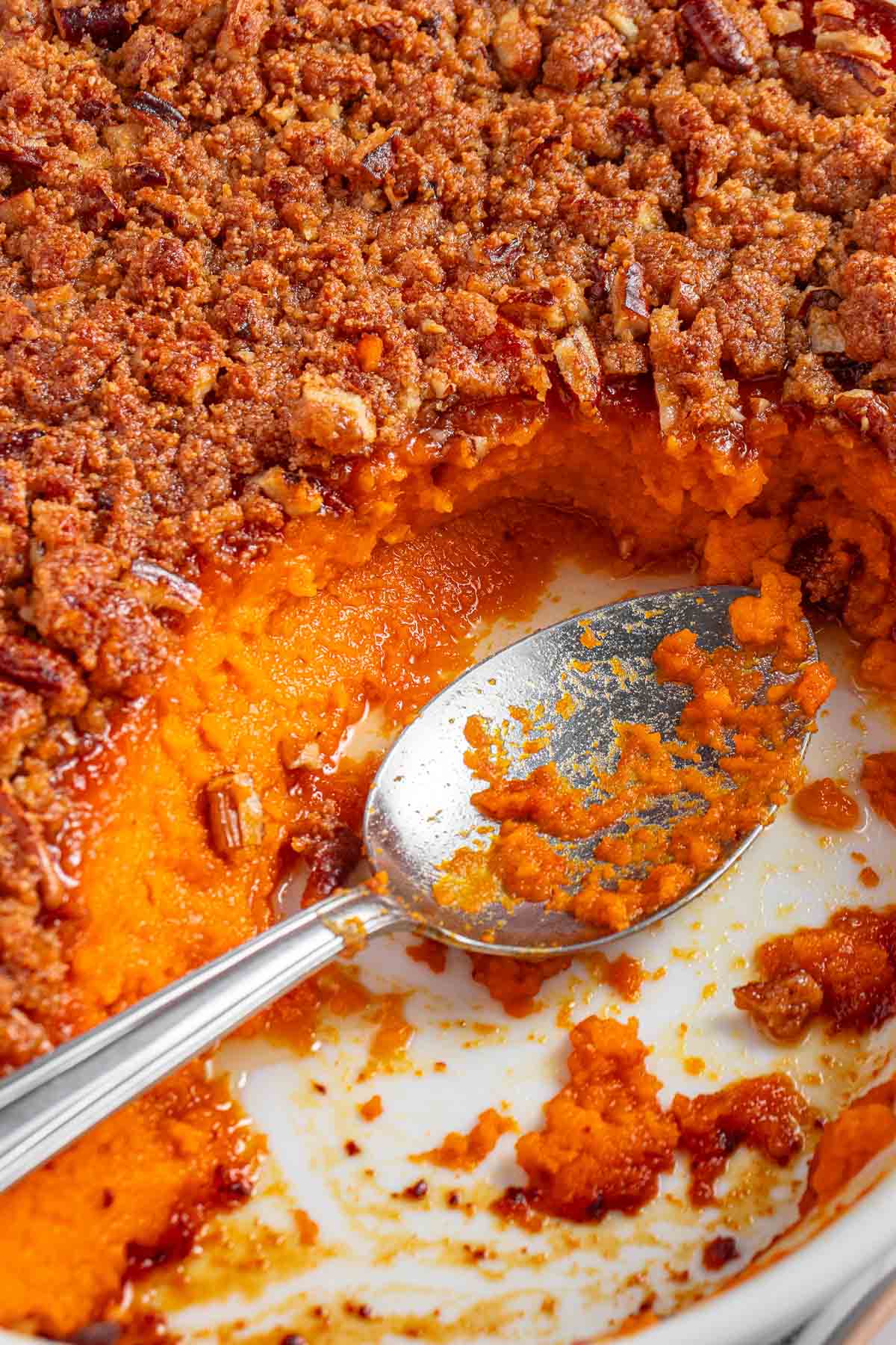 Missing spoonful from dish of Old-Fashioned Sweet Potato Casserole with pecan topping.