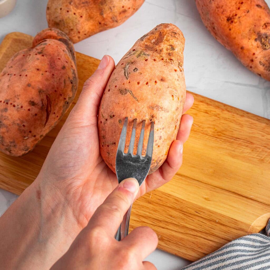 Pricking sweet potato with a fork.