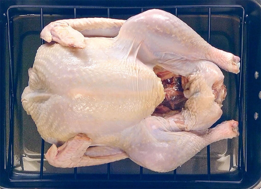 Raw turkey patted dry and waiting in roasting pan.