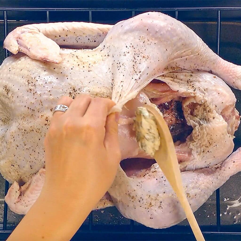 Spreading sage butter under turkey skin for Bacon Wrapped Turkey.