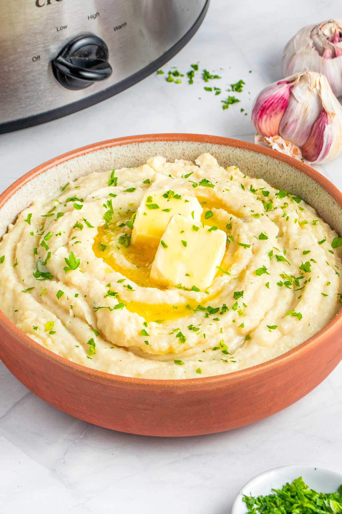 Crock Pot Mashed Potatoes in serving bowl with crockpot in background.