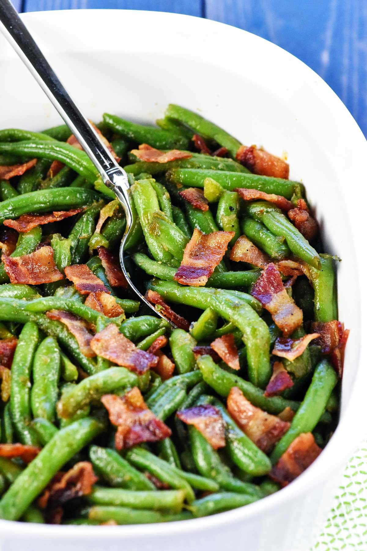 Green bean and bacon recipe in dish with spoon.