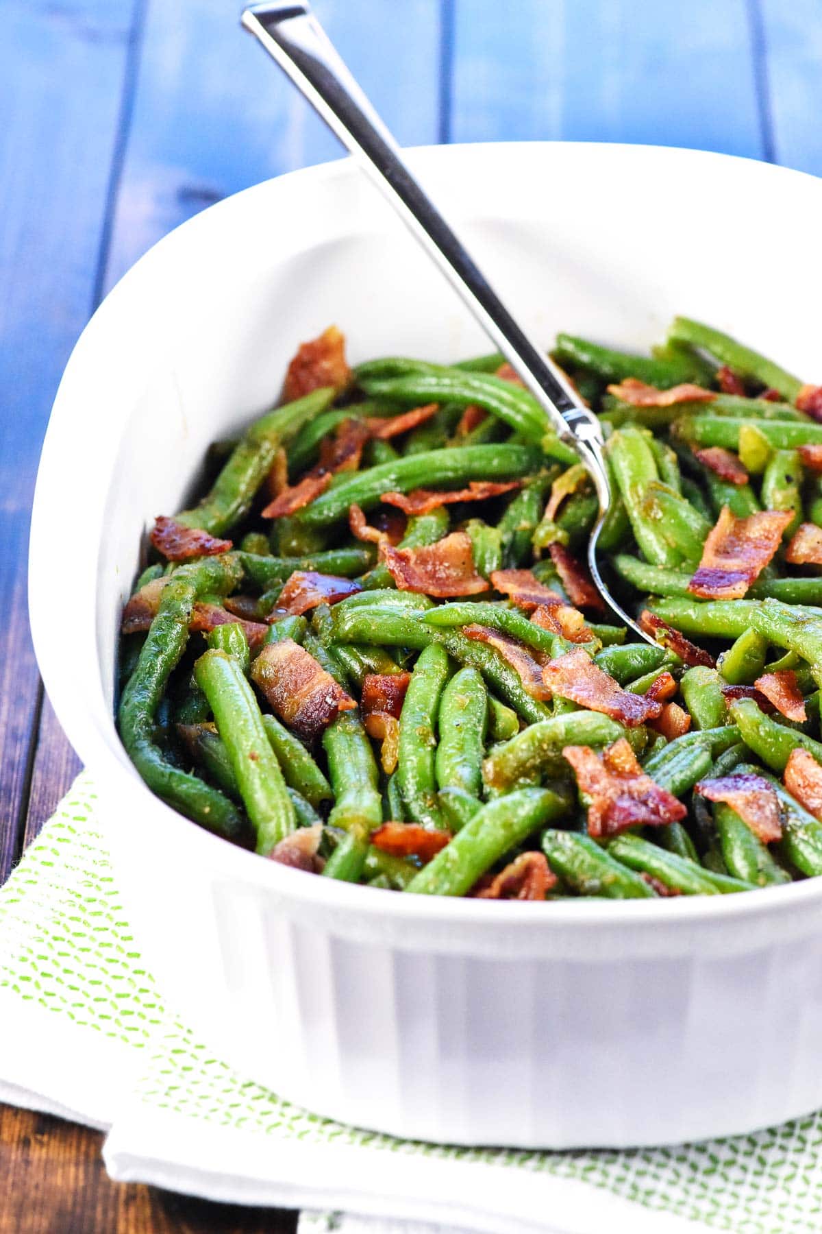 Bacon green beans in white dish with spoon.