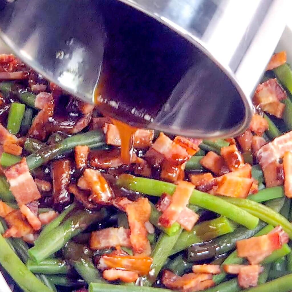 Pouring glaze over bacon green beans.