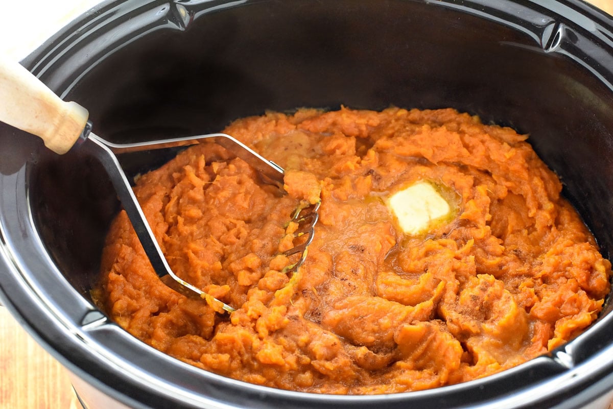 Mashing sweet potatoes in crock pot.