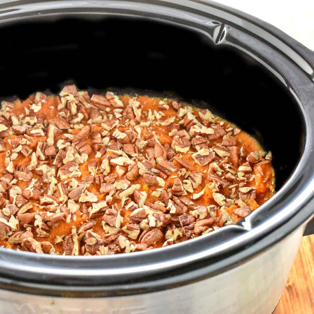 Slow Cooker Sweet Potato Casserole with topping of toasted pecans in crockpot.