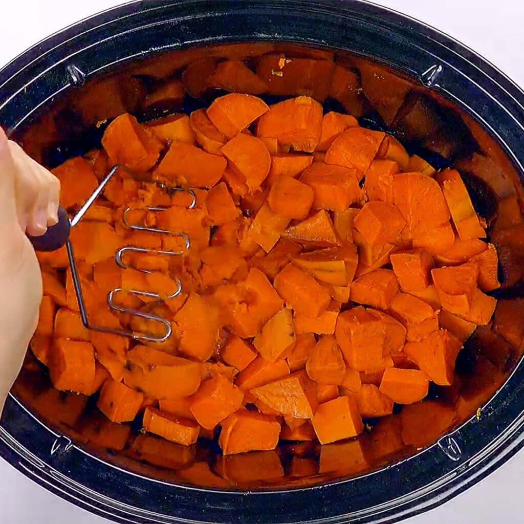 Mashing sweet potatoes for Slow Cooker Sweet Potato Casserole.