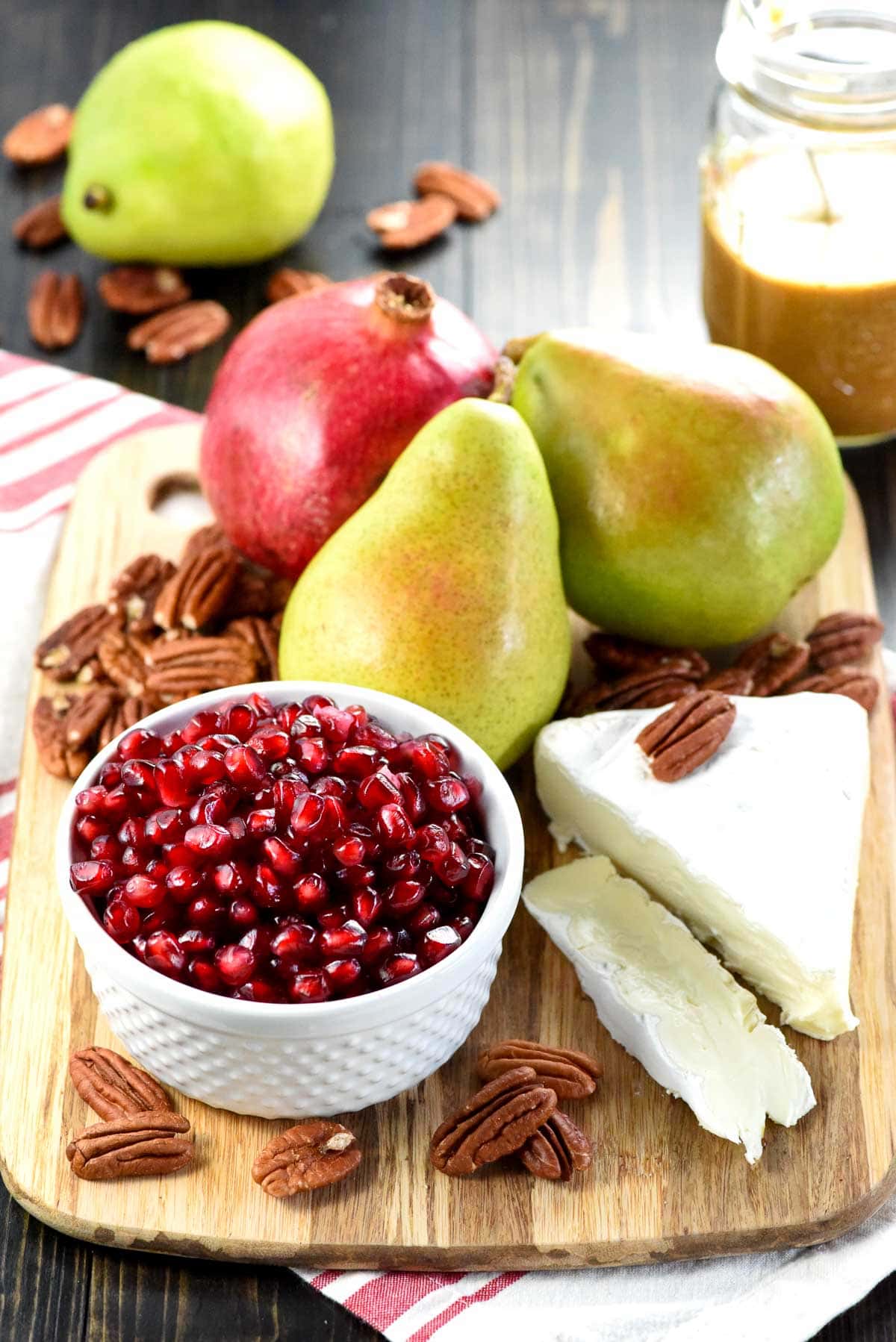 Pomegranate, pears, pecans, brie, and homemade balsamic vinaigrette on table.