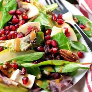 Thanksgiving Salad close-up with pomegranate, pears, pecans, brie, and homemade balsamic vinaigrette.