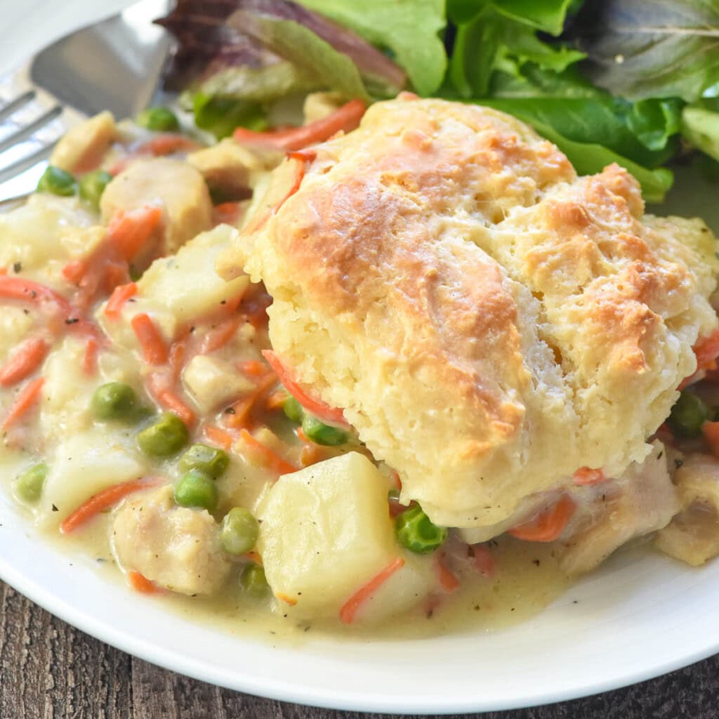 Chicken Pot Pie Casserole close-up on plate with homemade biscuit and gravy.