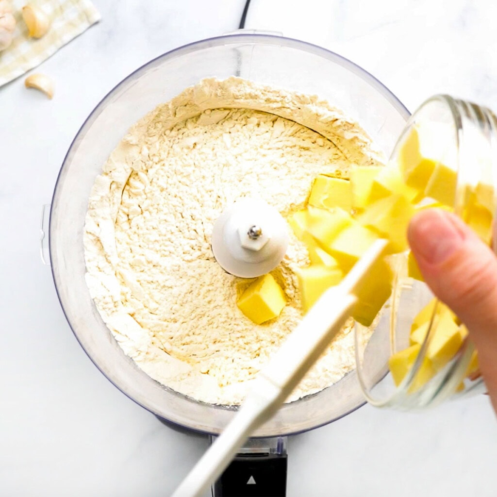 Adding butter to flour in food processor for biscuit topping.