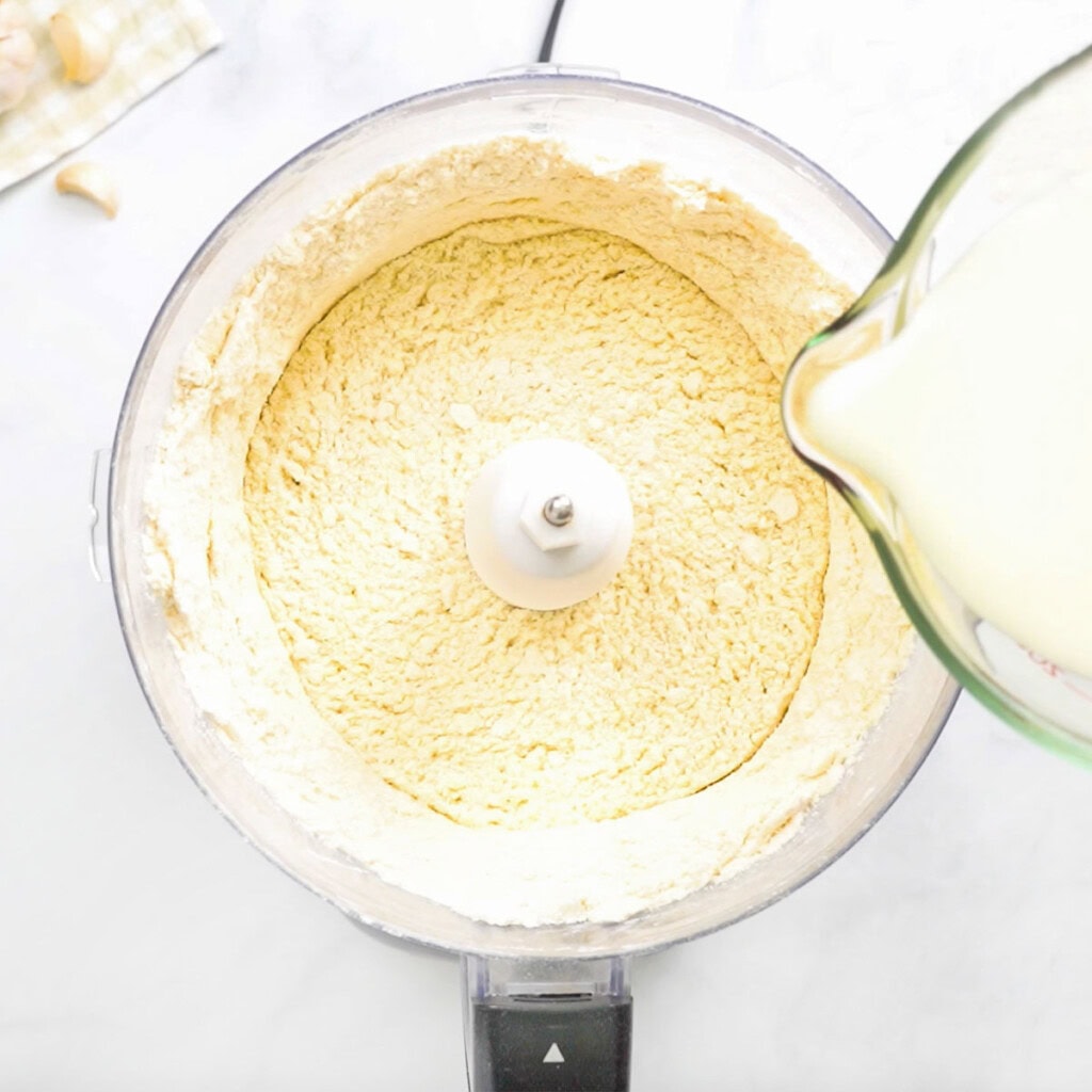 Adding milk to make homemade biscuit dough.