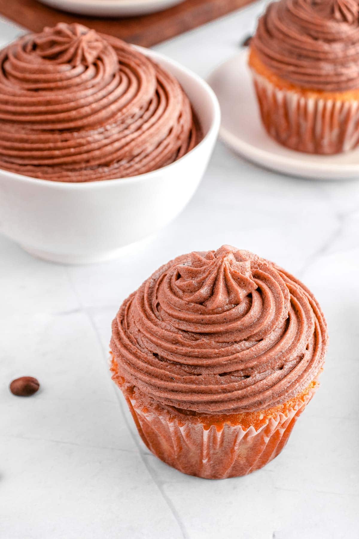 Cream cheese chocolate frosting on cupcakes and in bowl.