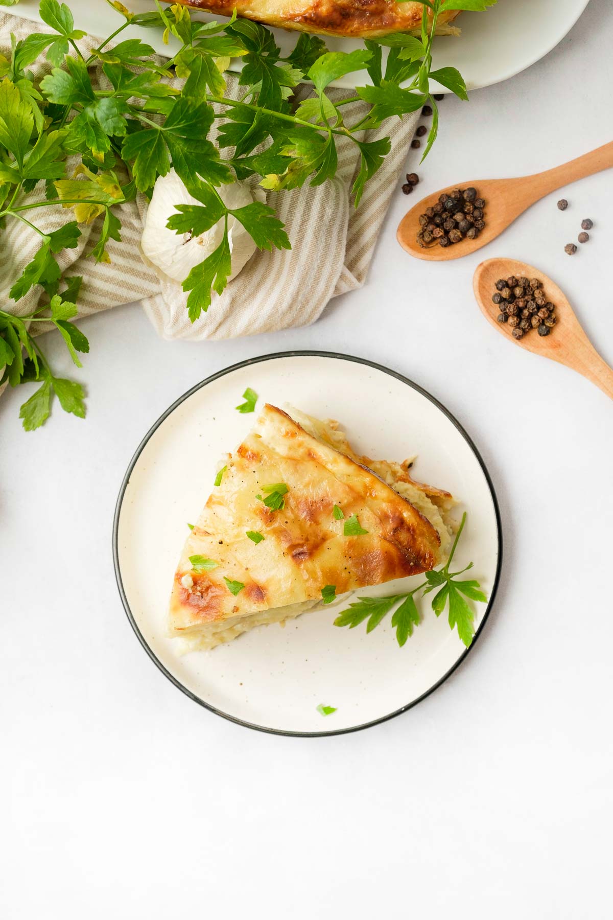 Slice of Gruyere Scalloped Potatoes on plate with parsley.