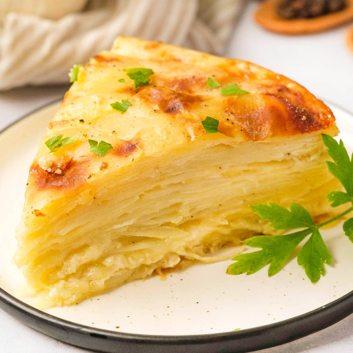 Gruyere Scalloped Potatoes on plate with parsley sprig.