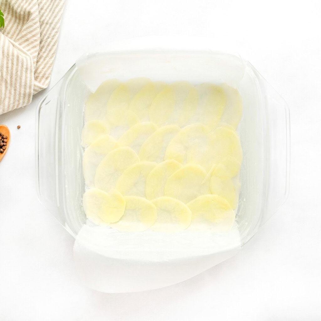 Layering potato slices in baking dish for Gruyere Scalloped Potatoes.