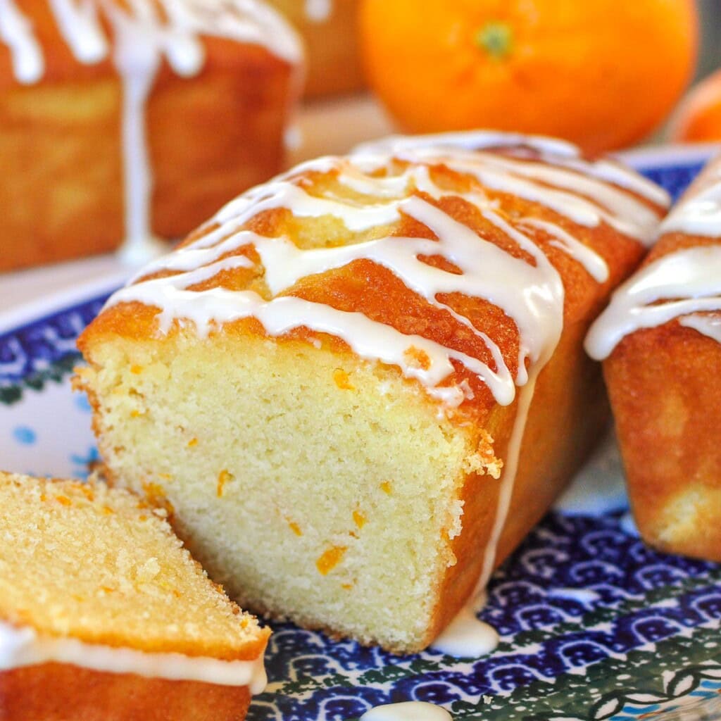 Orange Pound Cake with orange glaze and orange zest, sliced on platter.