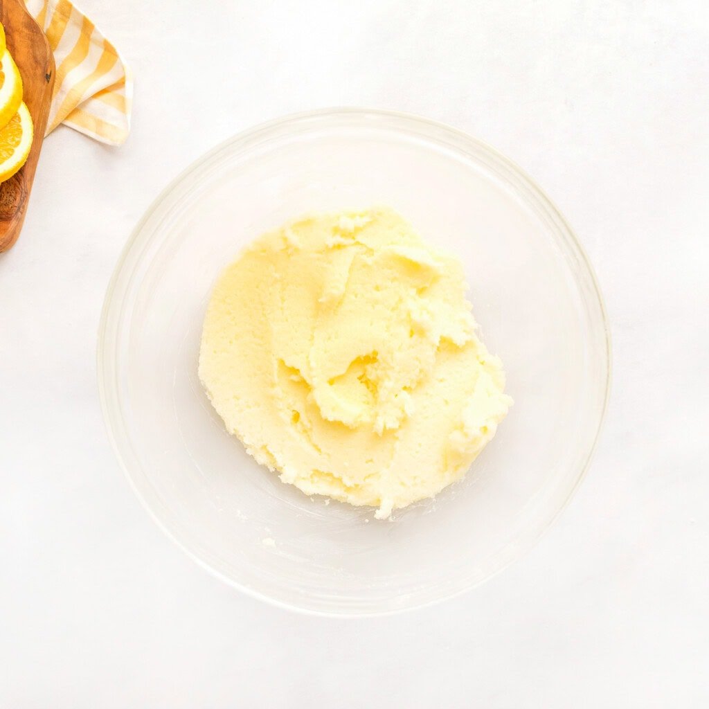 Sugar beaten into butter in glass bowl.