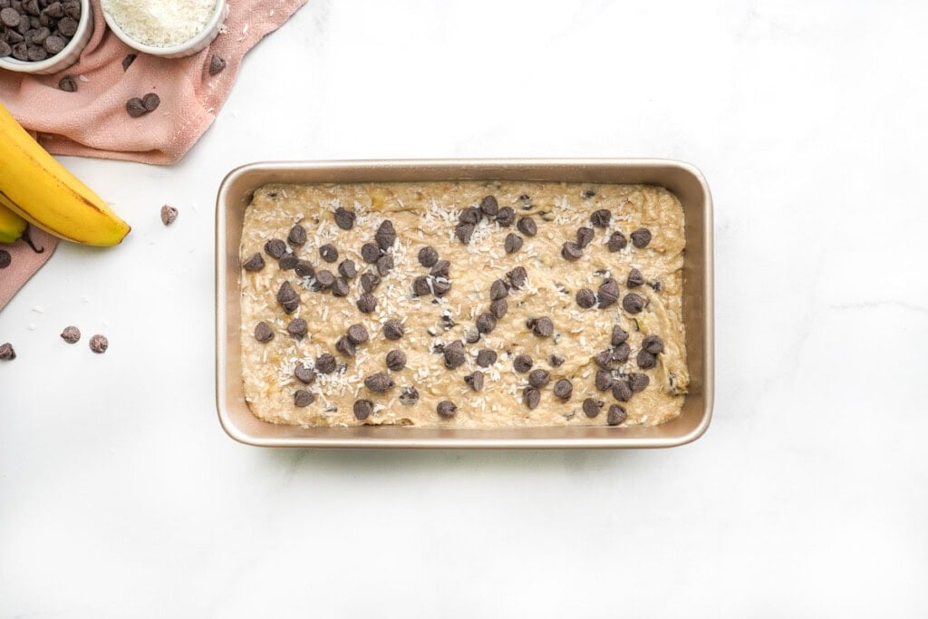 Chocolate Chip Banana Bread batter in pan with extra chocolate chips.