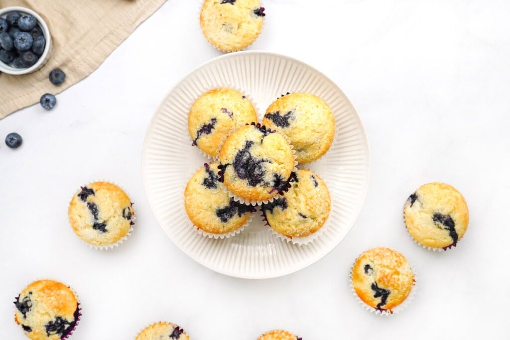 Easy blueberry muffin recipes on plate and scattered on table.