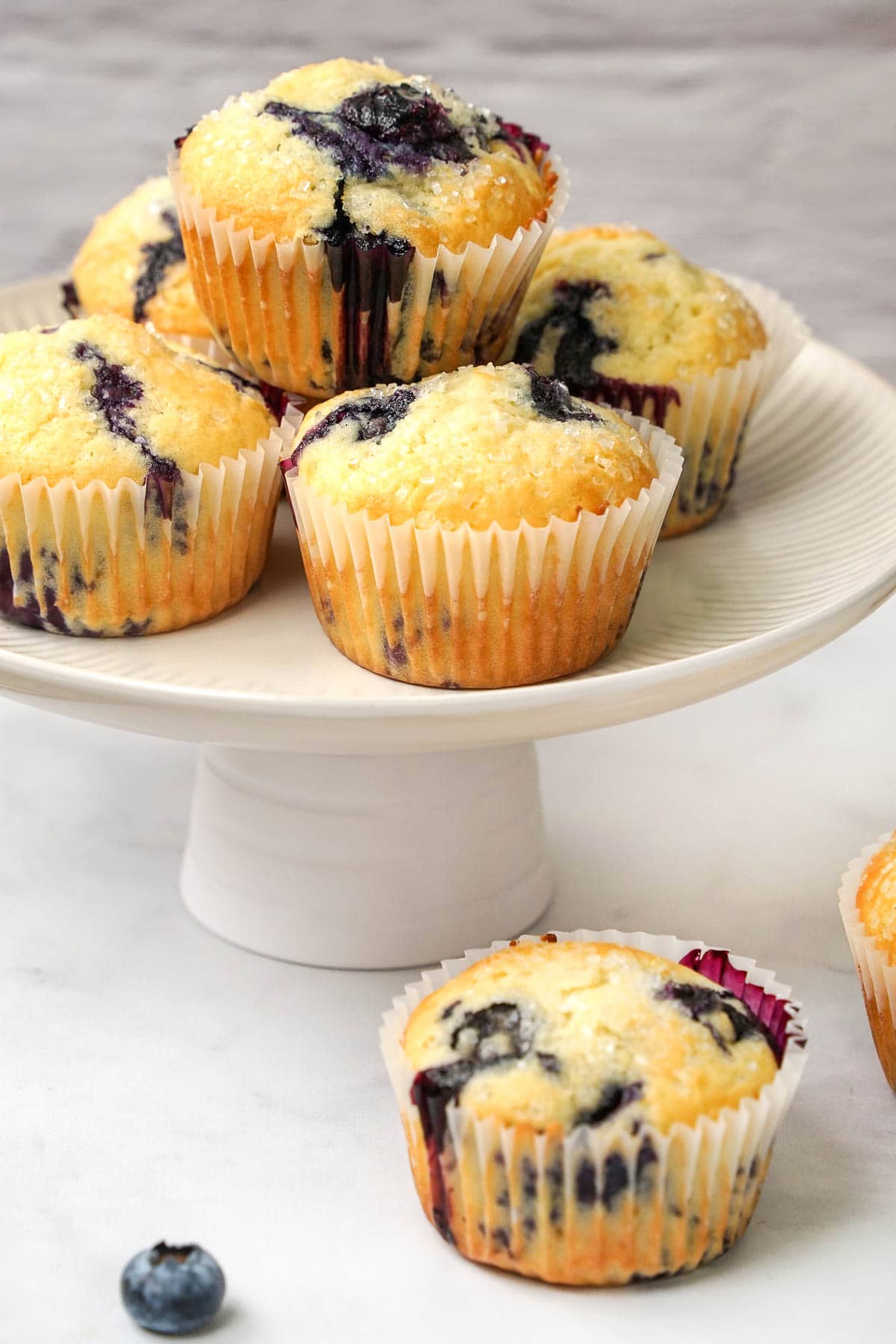 Easy Blueberry Muffins on platter with one on table.