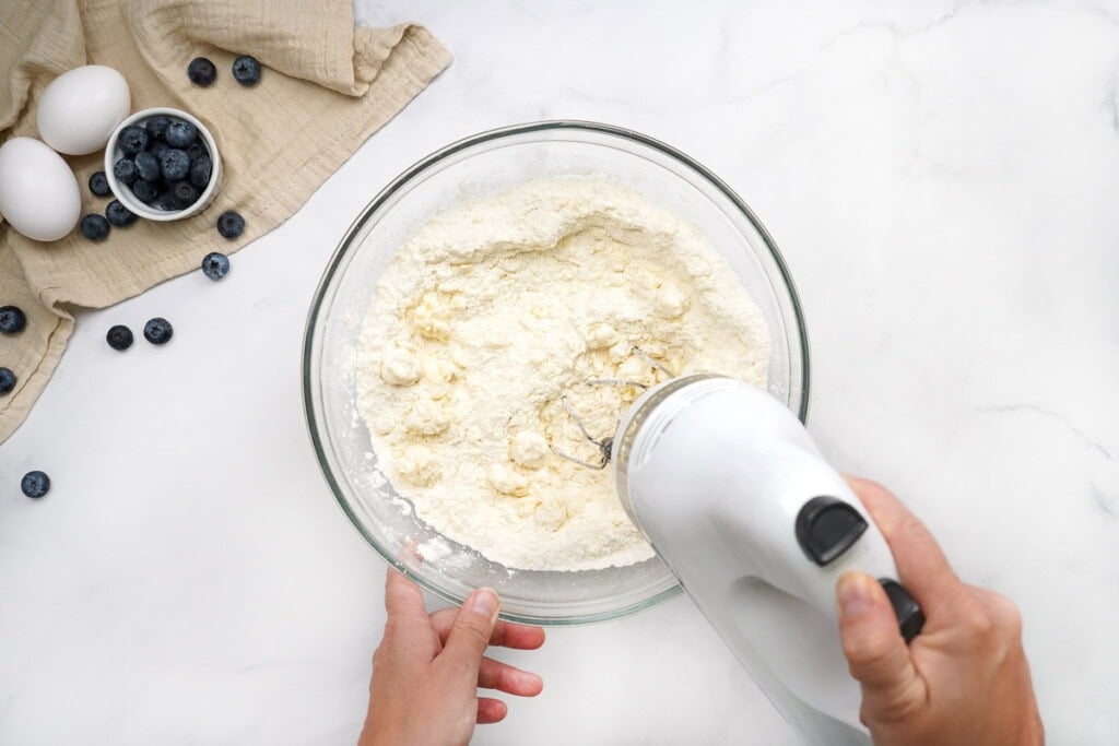 Blending softened butter into flour mixture for blueberry muffin recipe easy.