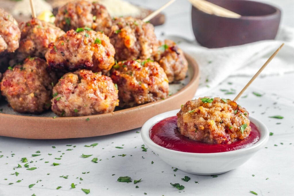 Baked Turkey Meatballs on platter and dipped in sauce.