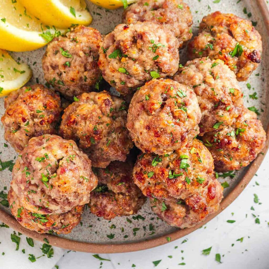 Baked Turkey Meatballs on platter with lemon and parsley garnish.