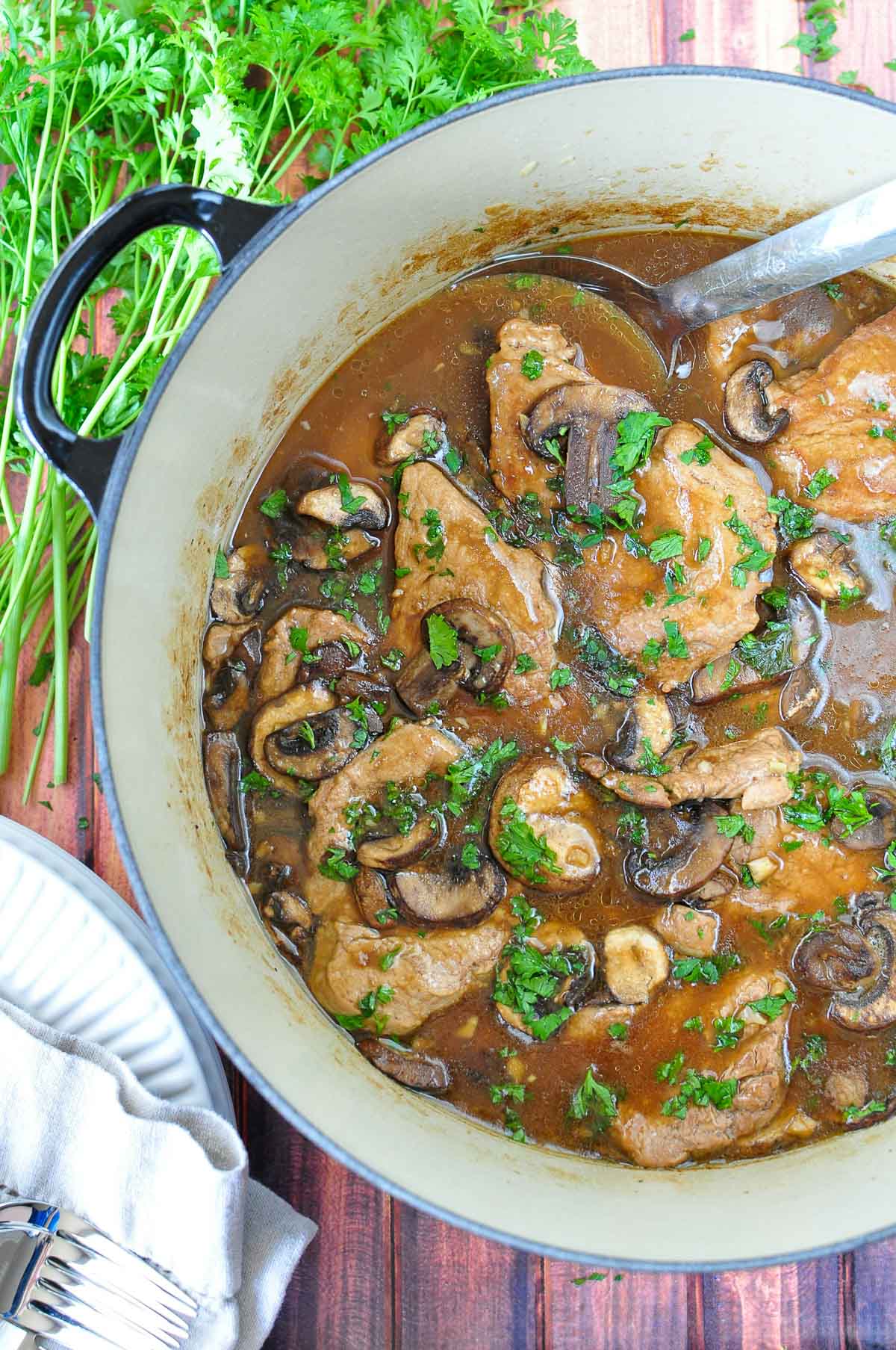 Pork Tenderloin Medallions with mushroom gravy in pot with parsley.